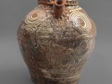 une image représentant un vase marron et blanc posé sur une surface grise