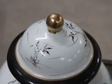 a white and black tea pot with a gold lid