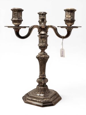 an antique silver plated candelab with three candles on a stand