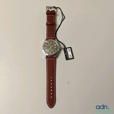 a close up of a watch on a white surface with a tag