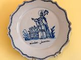 a blue and white plate with a picture of a woman holding a baby