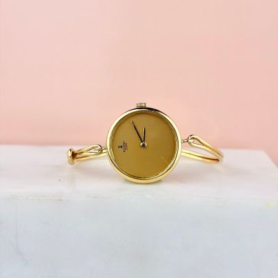 une montre-bracelet en or posée sur un bloc de marbre