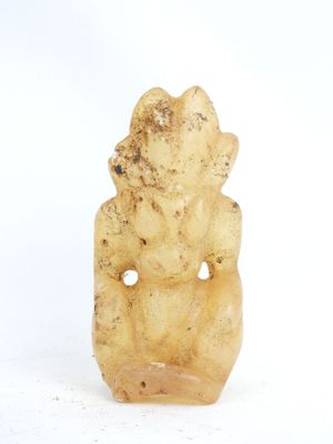 une image représentant une petite statue d'une personne assise sur une surface blanche