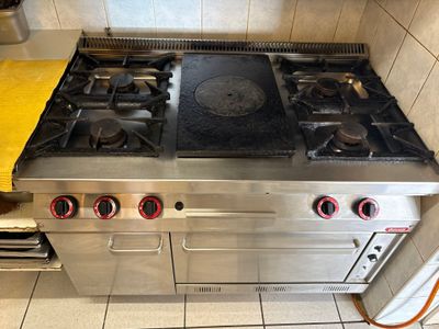 une cuisinière en acier inoxydable à quatre feux et une serviette jaune posée sur le plan de travail