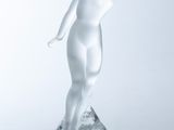statue of a woman standing on a clear base with her hands on her head