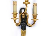 gold and black wall sconce with a woman holding a candle