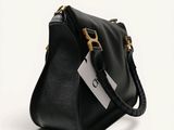 a black handbag with a tag on it sitting on a white surface