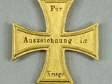 an image of a gold cross with a ribbon around it