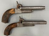 deux vieux revolvers sont posés sur une surface blanche