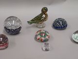 a small bird sitting on top of a table next to many glass balls