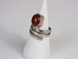 silver ring with a red stone on top of a white cone