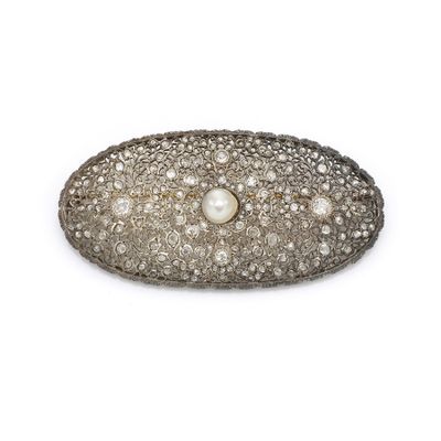 a close up of a pearl and diamond broochle on a white background
