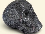 black rock with a skull on top of it sitting on a white surface