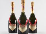 three bottles of champagne are lined up on a white surface