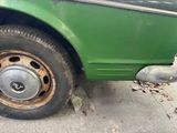 a close up of a green truck with a flat tire