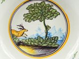 a plate with a picture of a deer and a tree on it