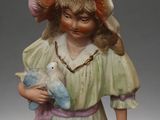 a figurine of a young girl holding a teddy bear