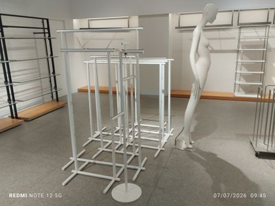 a white mannequin standing next to a rack of clothes