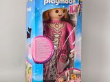 poupée dans la boîte d'une poupée Playmobil, vêtue d'une tenue rose et de chaussures roses