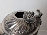 a silver tea pot with a lid on a table