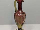 a red and gold vase sitting on a white table