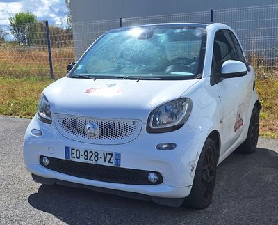 a small white car that is parked on the side of the road