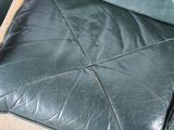 a close up of a green leather chair with a black seat
