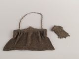 brown knitted purse with chain strap and owl figurine next to it