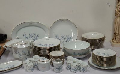 many plates and cups on a table with a statue in the background