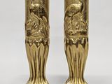 paire de vases dorés sur fond blanc, avec un oiseau représenté sur l'un des vases