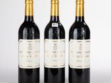 trois bouteilles de vin rouge sont posées côte à côte sur une surface blanche