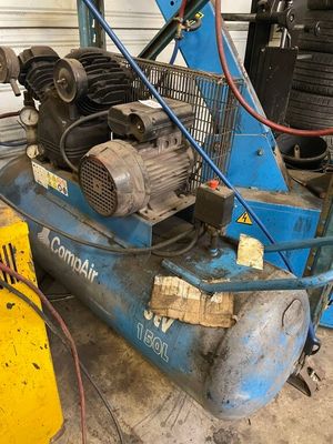 a blue air compressor sitting on the ground next to a yellow machine