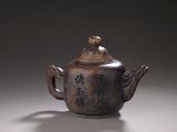 a brown teapot with writing on it sitting on a table
