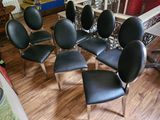 six black leather chairs sitting in a circle on a wooden floor