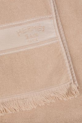 La serviette est de couleur beige et comporte une bande blanche.