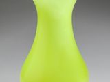 un vase en verre jaune posé sur une surface blanche