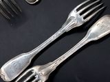 four forks and two spoons on a black table