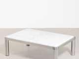 une table basse en marbre blanc posée sur un sol en béton