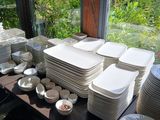 many plates and bowls on a table in front of a window