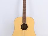 une guitare acoustique posée sur une surface blanche