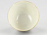 a white bowl with a gold rim on a white surface