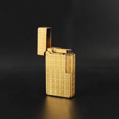 briquet doré posé sur une surface noire, sur fond noir