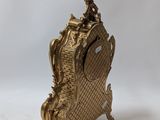 an antique brass clock on a stand on a white background