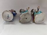 three figurines of people riding a train on a white surface