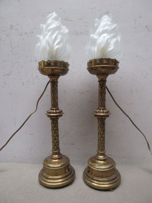 une paire de bougies anciennes en laiton ornées de plumes blanches, posées sur une table