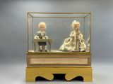 deux poupées dans une vitrine posée sur une table