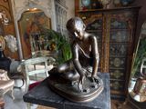 a bronze statue of a woman sitting on a table