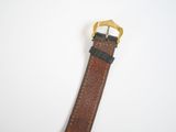 leather watch strap with gold buckle on a white background