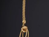 a close up of a gold necklace with a knot on it