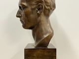 a bronze busturine of a man ' s head on a wooden base
